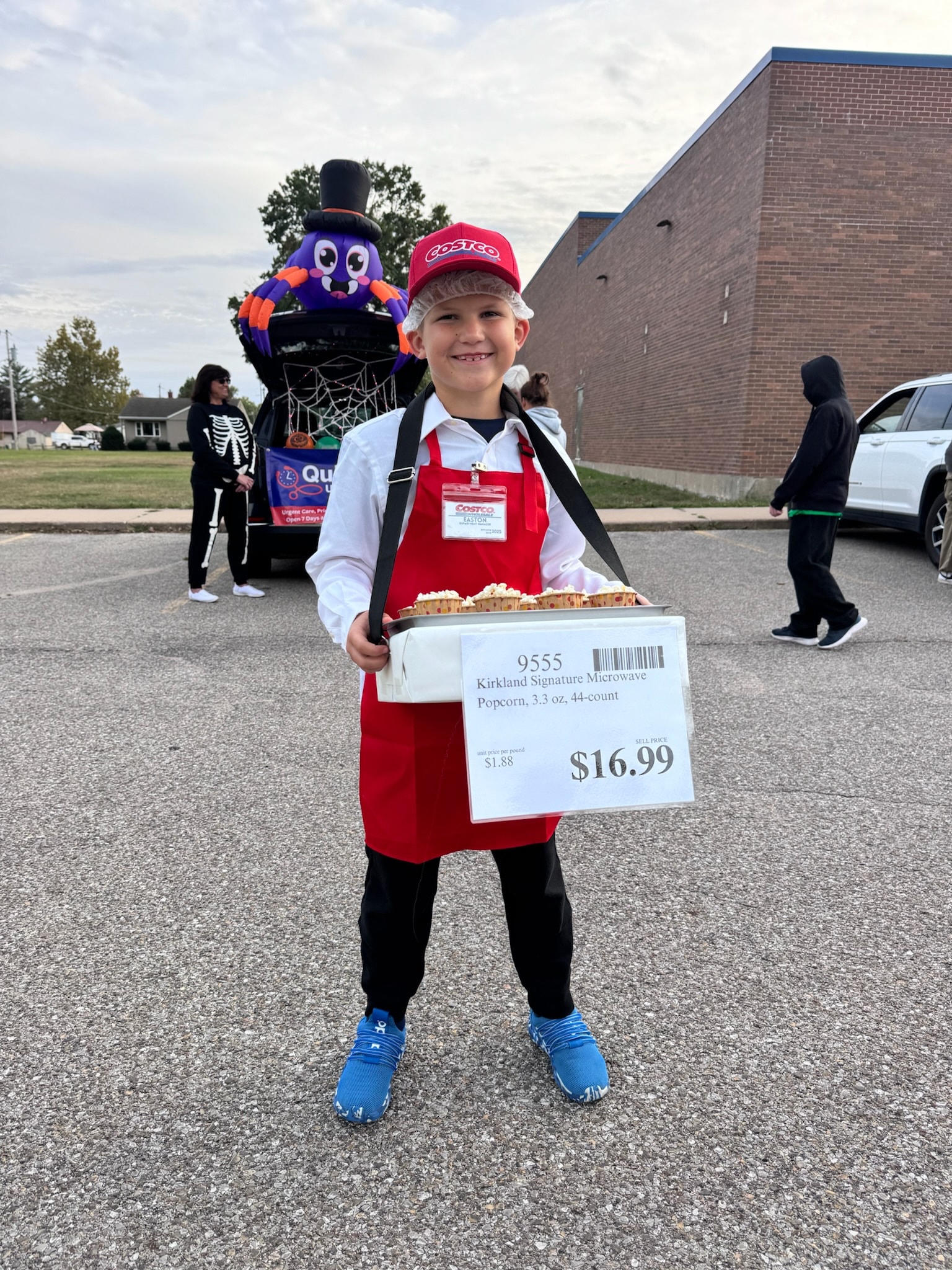 Child in a Costco costume handing out popcorn at Trunk or Treat